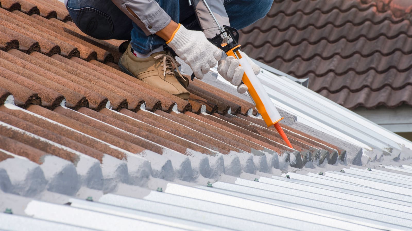 Roofer repairing tiles on a pitched roof