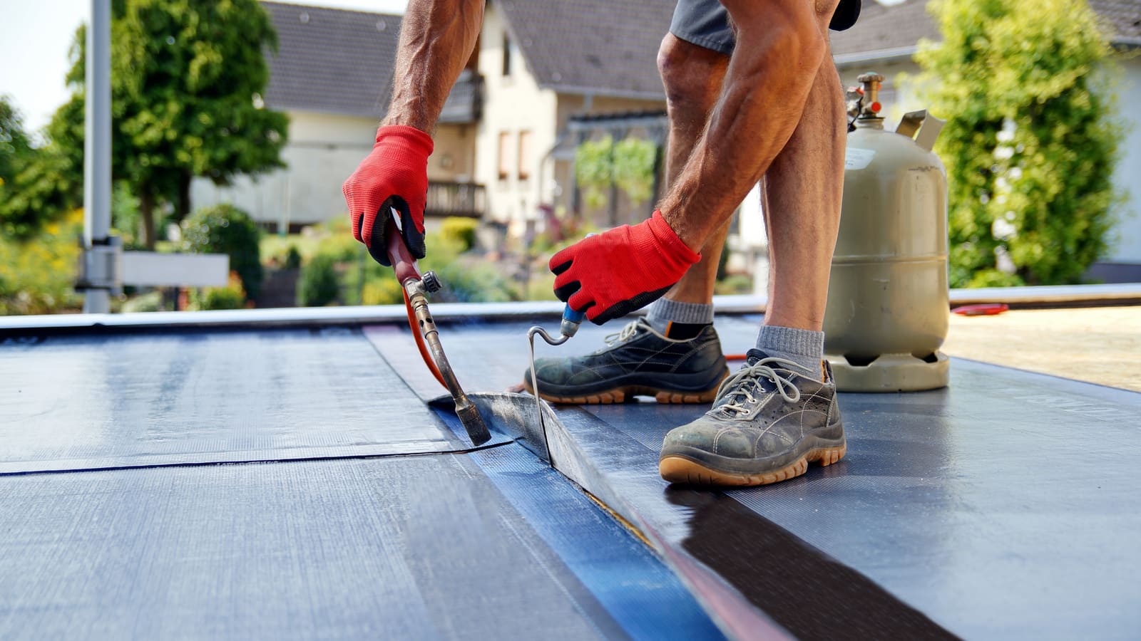Roofer applying torch-on felt to a flat roof